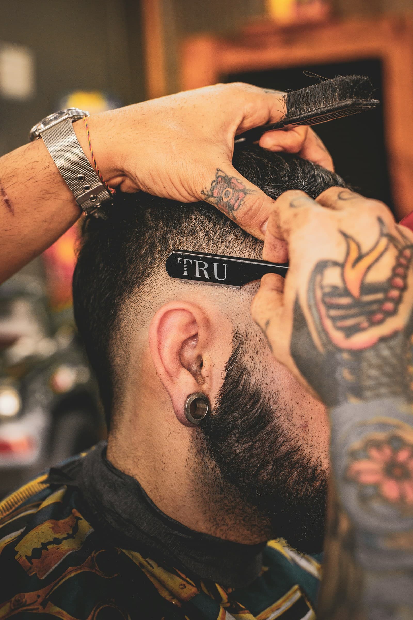 A barber cleaning up a fade with a straight razor.