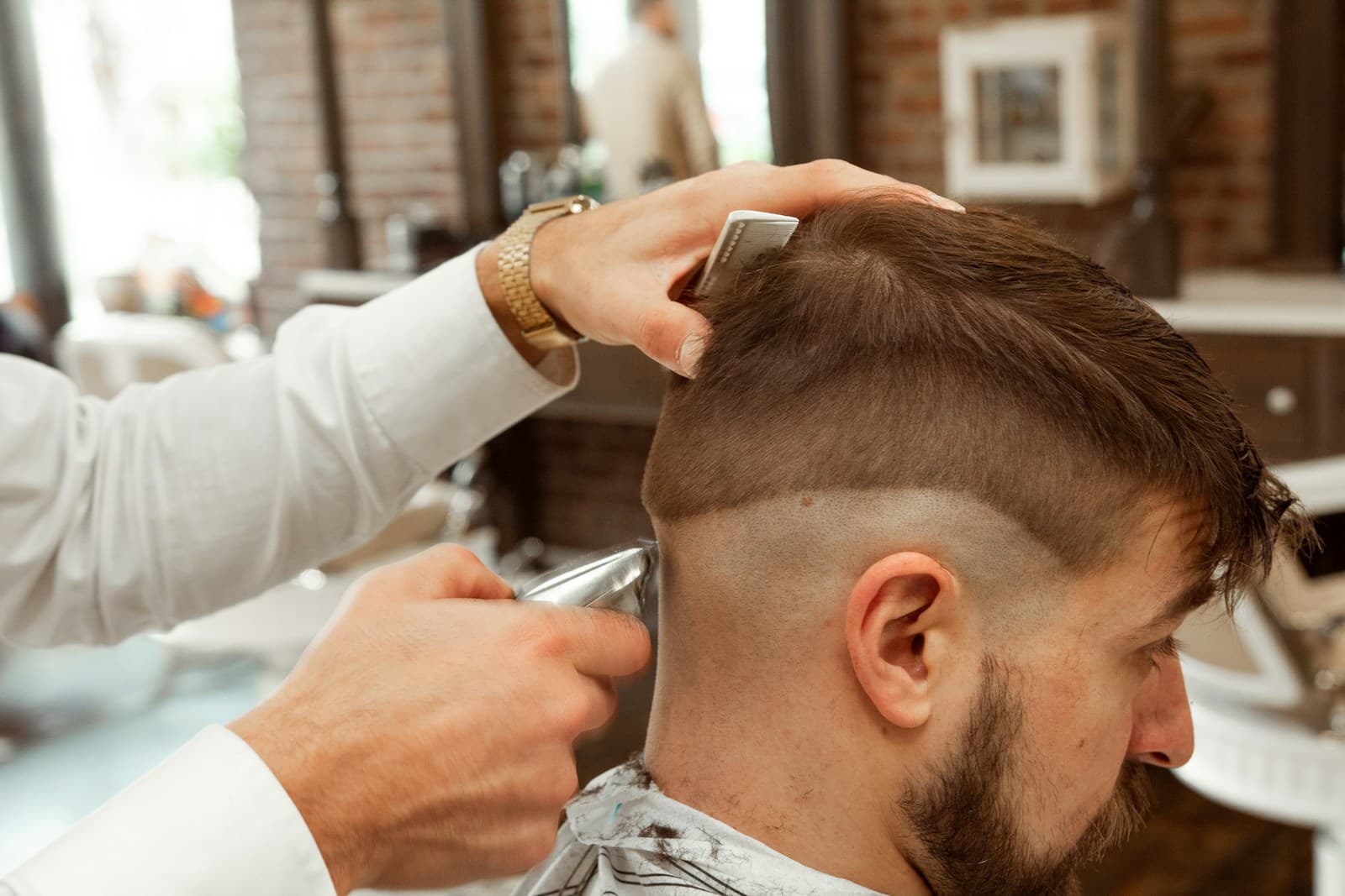 A barber clipping the back of a client's head.